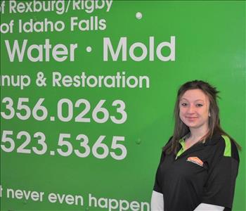 Female employee smiling in front of a SERVPRO truck