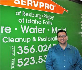 Male employee smiling in front of a SERVPRO truck